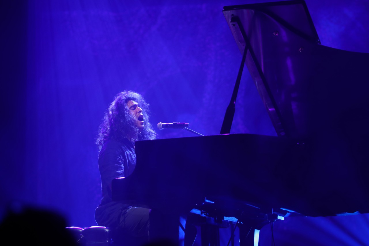 Dutcher singing while playing the piano on stage.