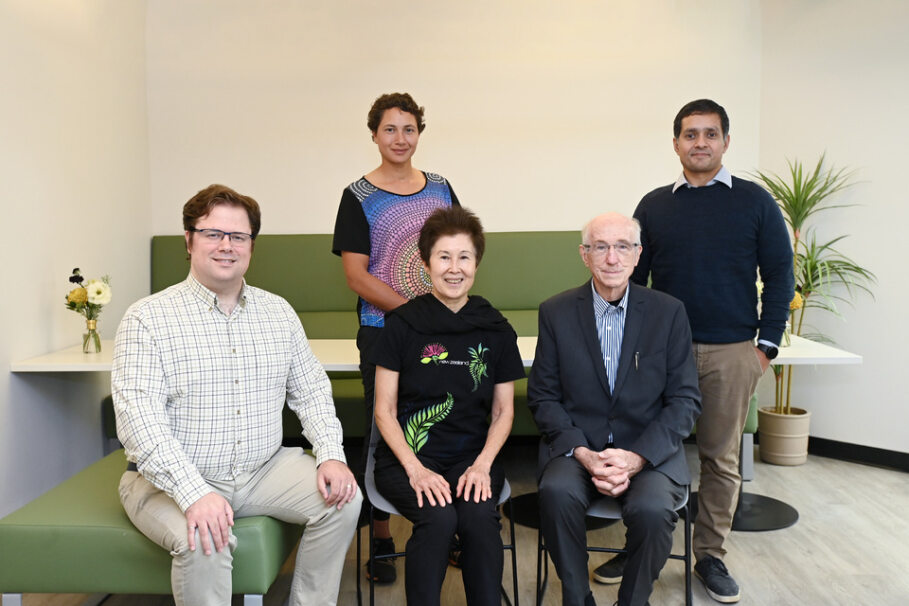 A diverse group of donors pose for a photo; three people are seated in chairs in the front row and two stand in the back.