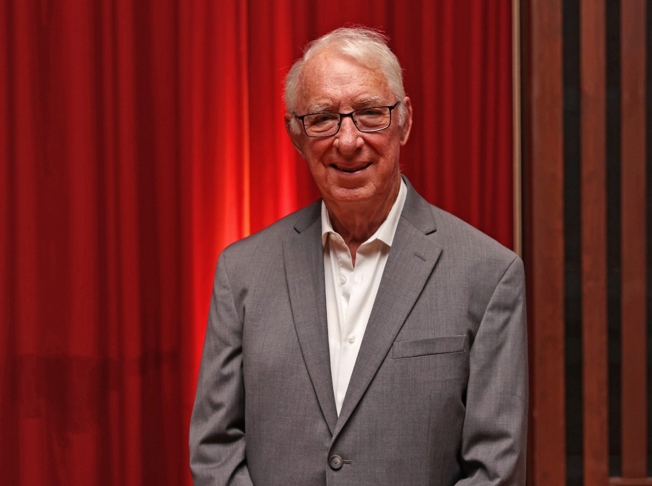 Shaw at a law alumni event standing in front of a red stage curtain.