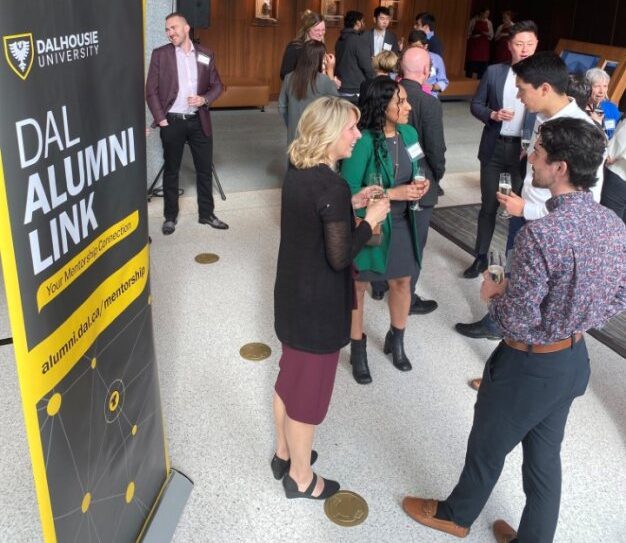 Four people in business attire walk out of the Dal Management building, two-by-two, in conversation.