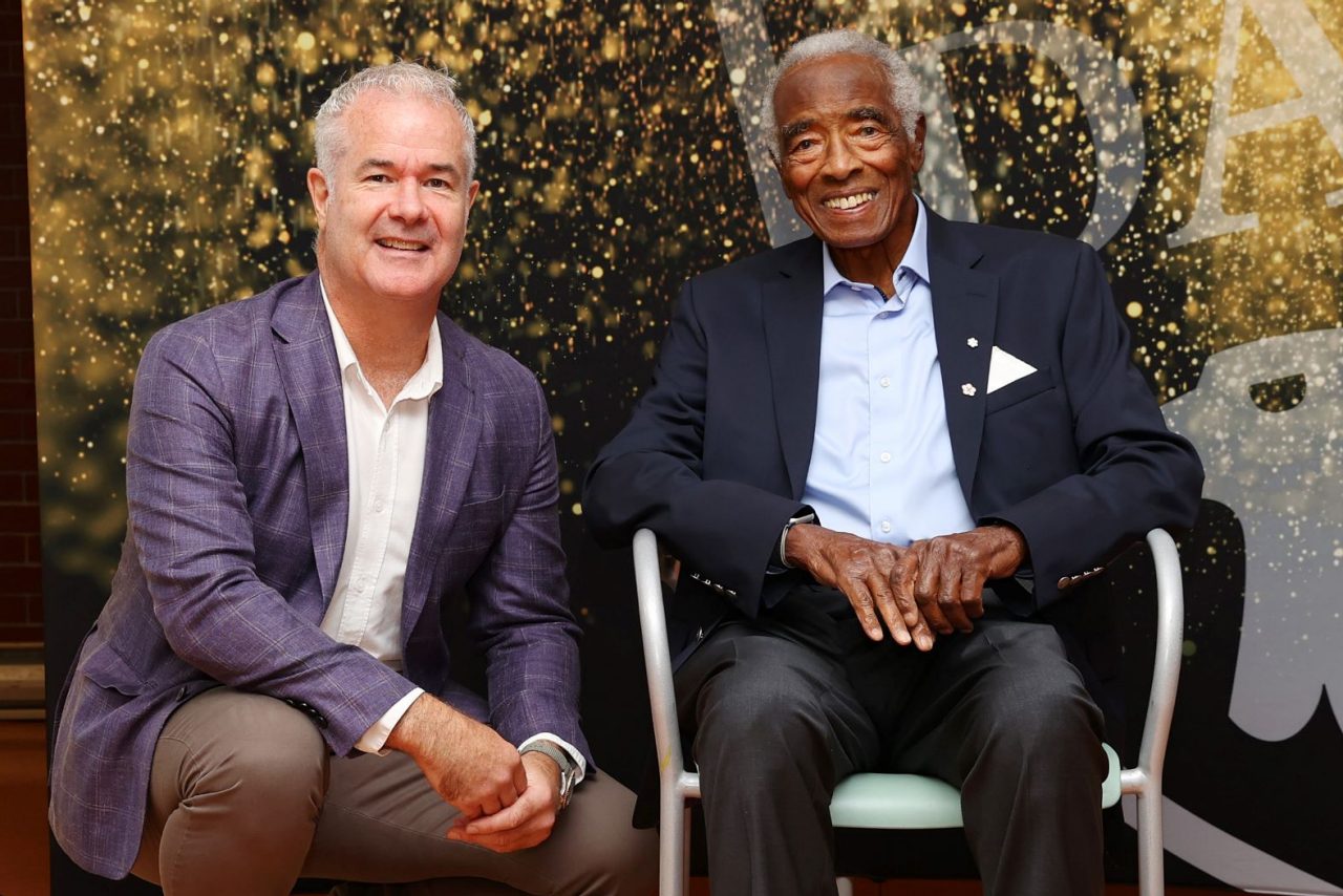 Dawe and Oliver, seated in chair, together at an event. 