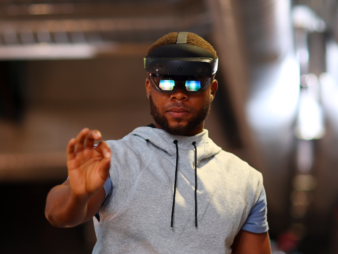 A man wearing a virtual reality headset reaches out to grab something