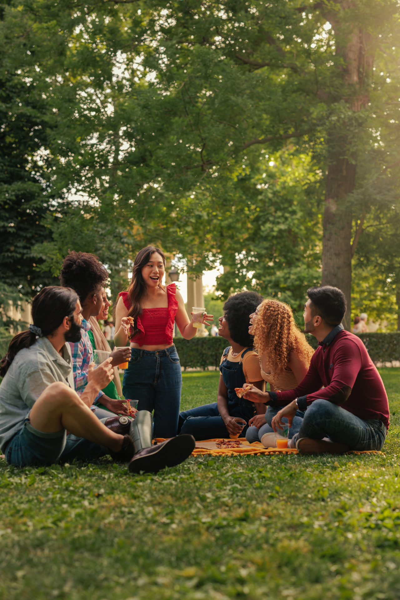 A young adult excited group of multiethnic friends enjoying time outdoors having a picnic
